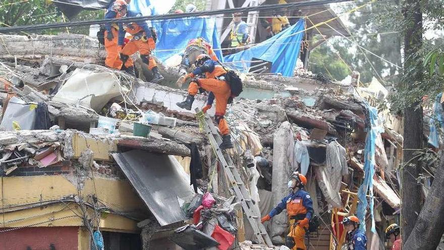 Miembros de las brigadas de rescate buscan a las víctimas atrapadas entre los escombros de un edificio.