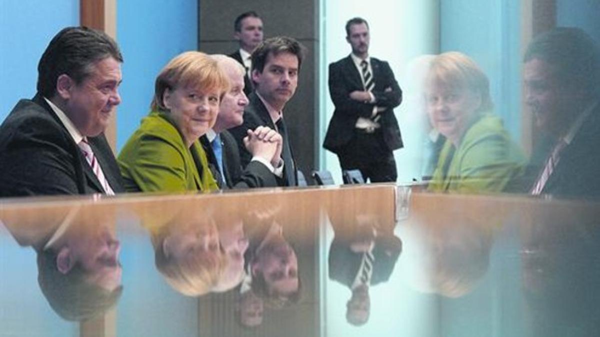 Los nuevos socios de la coalición, con Angela Merkel en el medio, en la presentación ayer del acuerdo en Berlín.