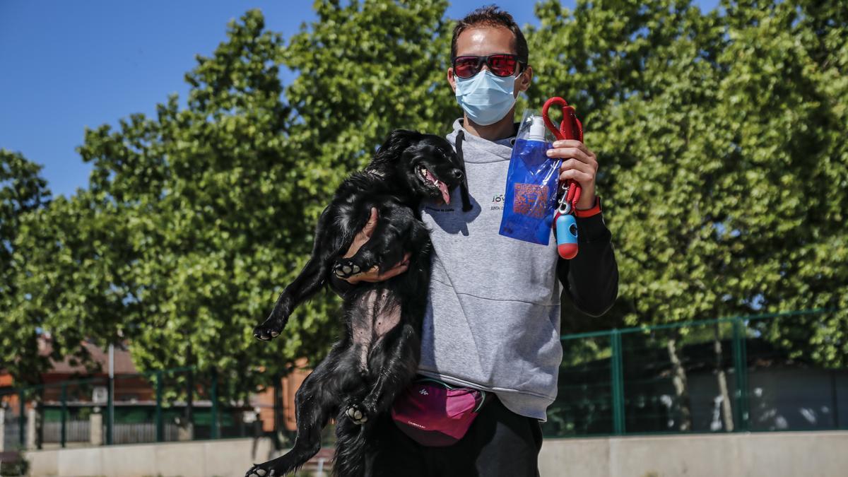 El propietario de un perro enseña a su mascota uno de los recipientes para limpiar la orina que esta semana empezará a repartir Conyser.