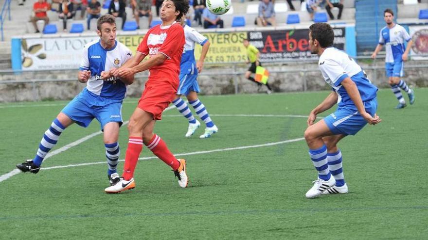 Jairo Cárcaba pelea un balón con Ginés en El Candín, con Kike atento a la jugada.