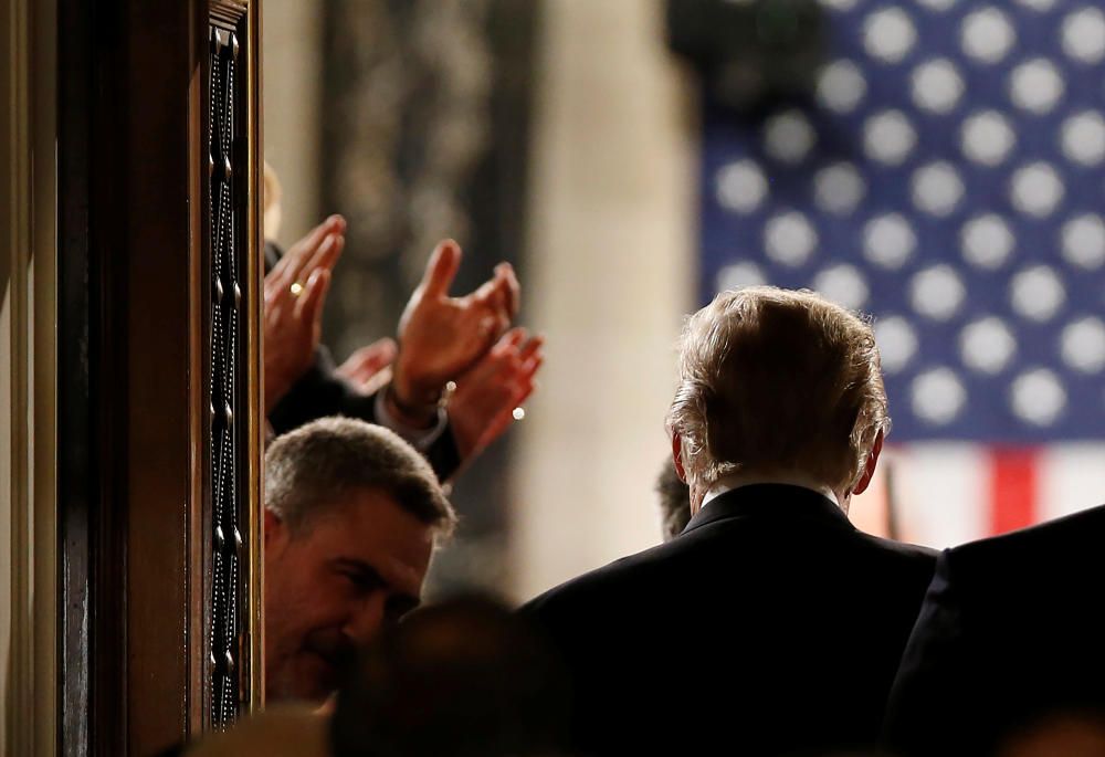 El presidente de EEUU Donald Trump entra a la cámara donde se celebra la sesión del Congreso aplaudido por sus ministros.