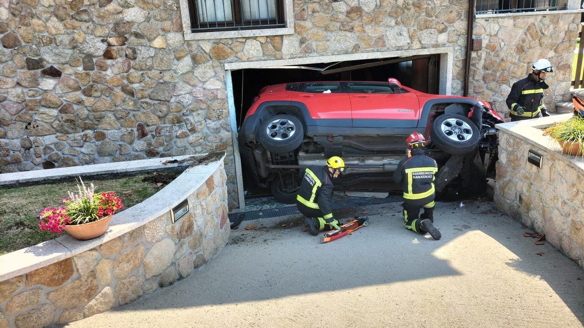 El coche quedó volcado y encajado en la puerta del garaje