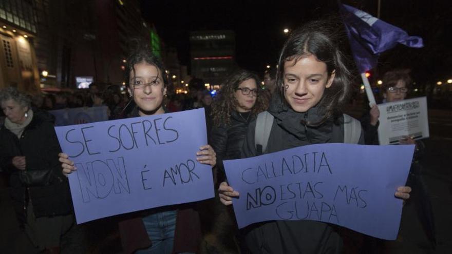 Dos jóvenes, con pancartas en contra de la violencia machista.