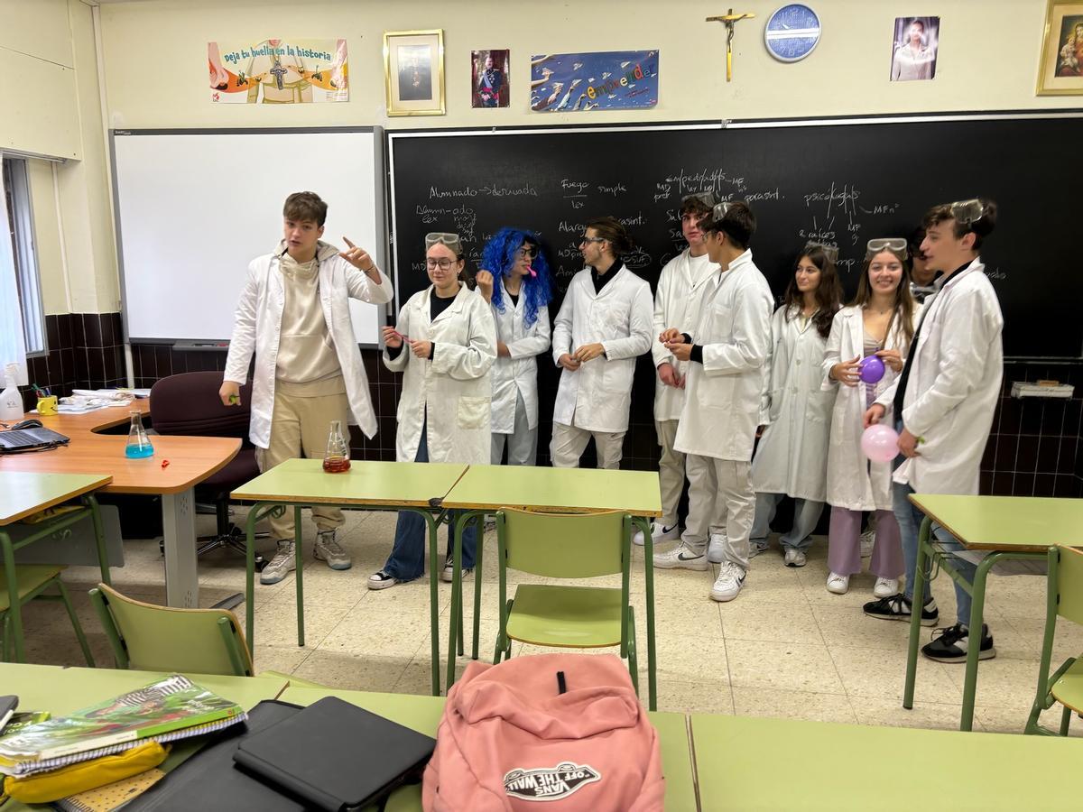 Los alumnos mayores, con bata, entran en un aula para explicar y poner en práctica un experimento.