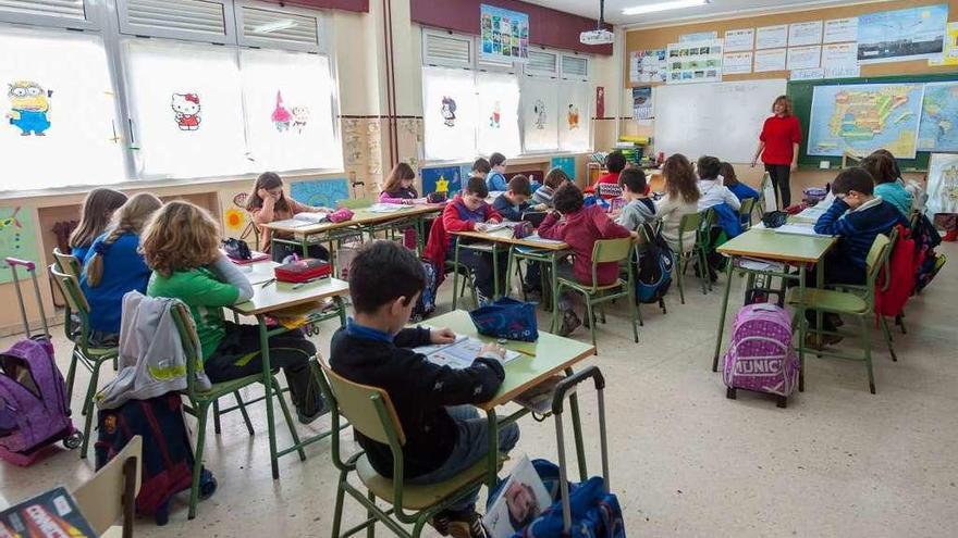 Un grupo de alumnos realiza sus ejercicios en un aula, ante la mirada de la maestra.