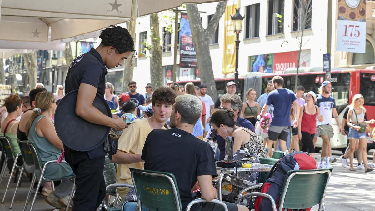 Barcelona. 12.08.2022. Barcelona Ambiente en Las Ramblas, en la foto un camarero cobra con tarjeta a unos clientes en una terraza frente al Liceu, esta mañana. Fotografía de Jordi Cotrina