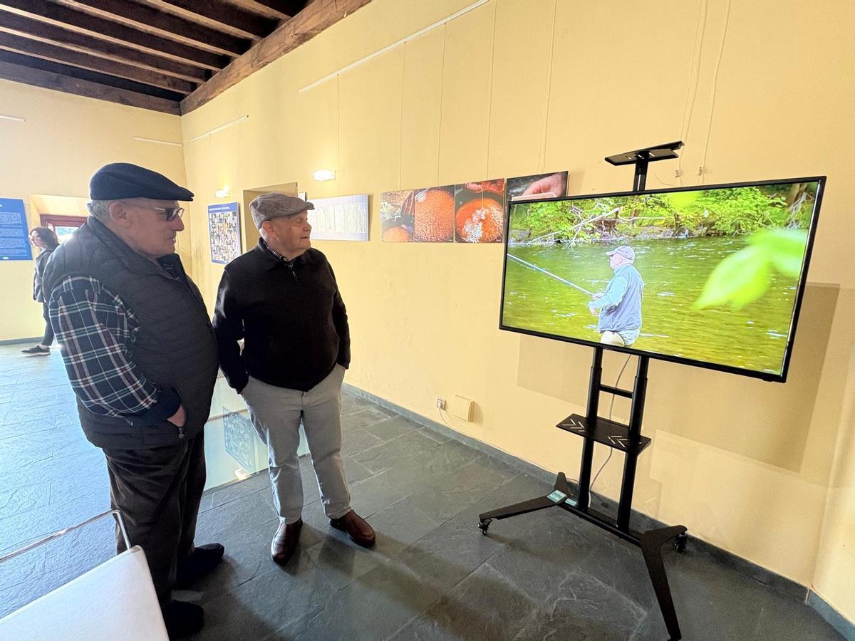 José Manuel Berdasco "Lulo el Bicho" y Benito Corolo observan el documental sobre la forma de pescar de Benito Corolo, que proyecta en la exposición sobre la pesca .