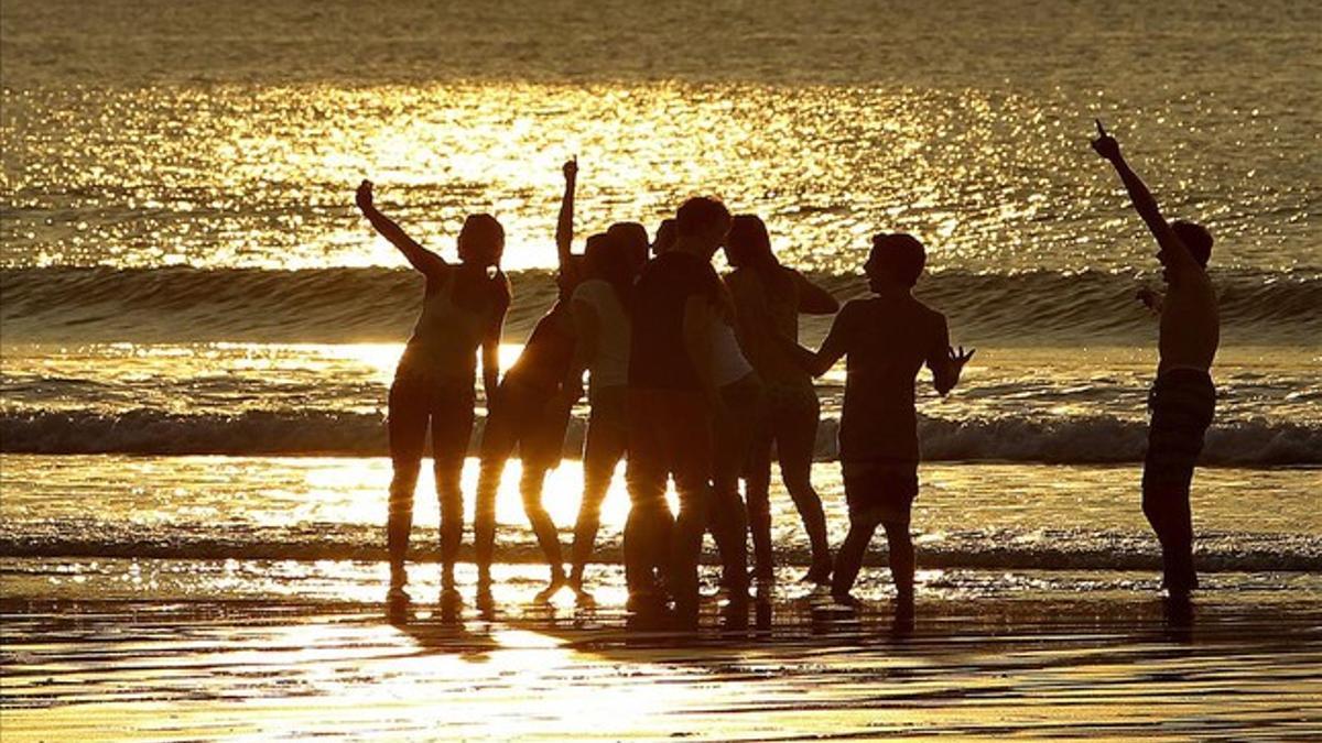 Un grupo de jóvenes disfruta del atardecer en la playa de La Concha de San Sebastián. Las temperaturas máximas han llegado a los 19 grados en la capital guipuzcoana