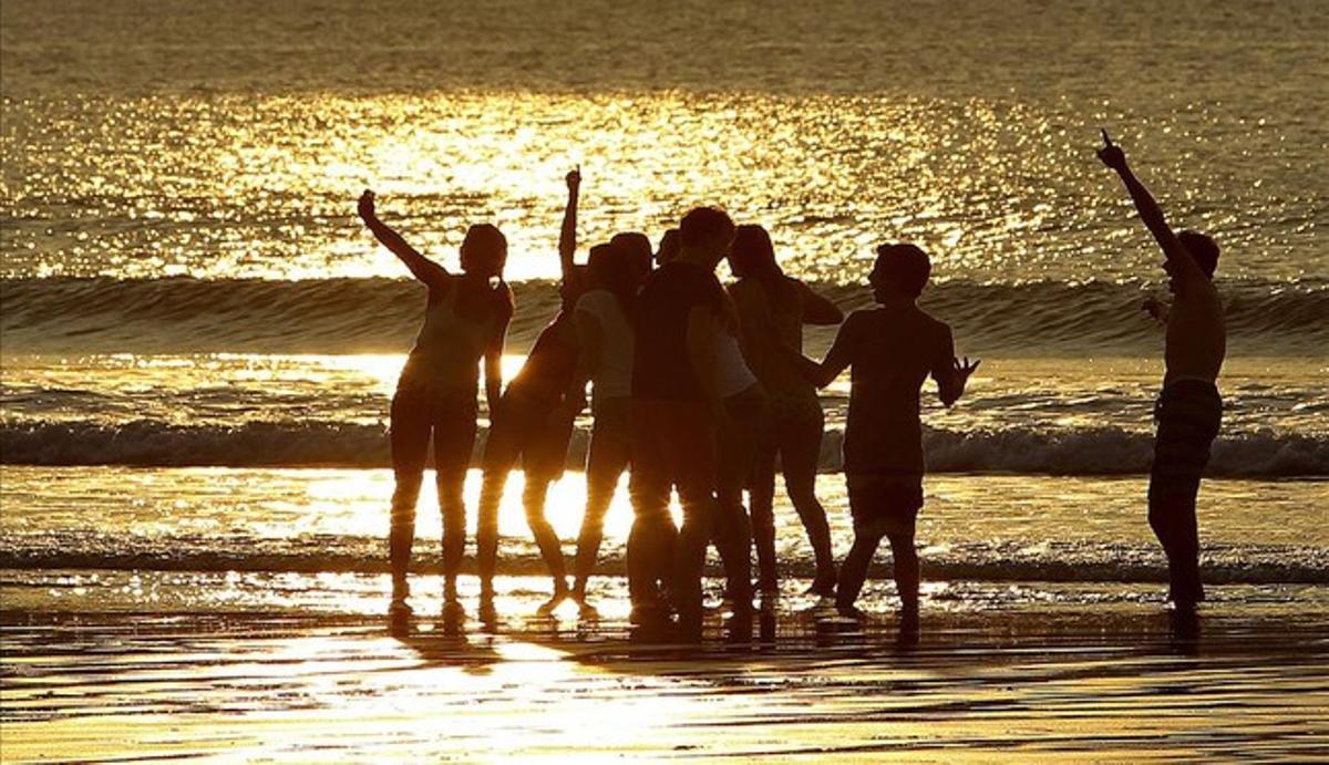 Un grup de joves disfruten del capvespre a la platja de La Concha de San Sebastián. Les temperatures màximes han arribat als 19 graus a la capital guipuscoana.