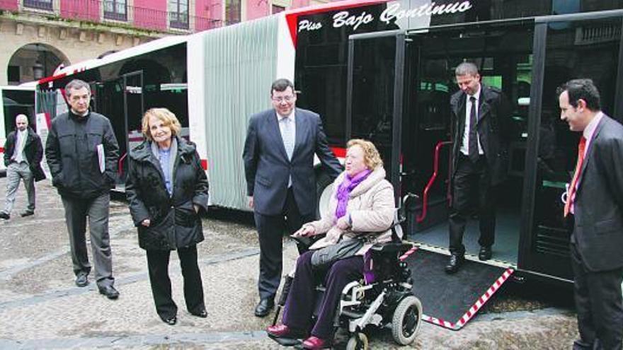 Paz Fernández Felgueroso, entre Luis Iturrioz y Santiago Martínez Argüelles, observa cómo Sila Murillo sube por  la rampa de uno de los nuevos autobuses articulados de la línea 12 de Emtusa.