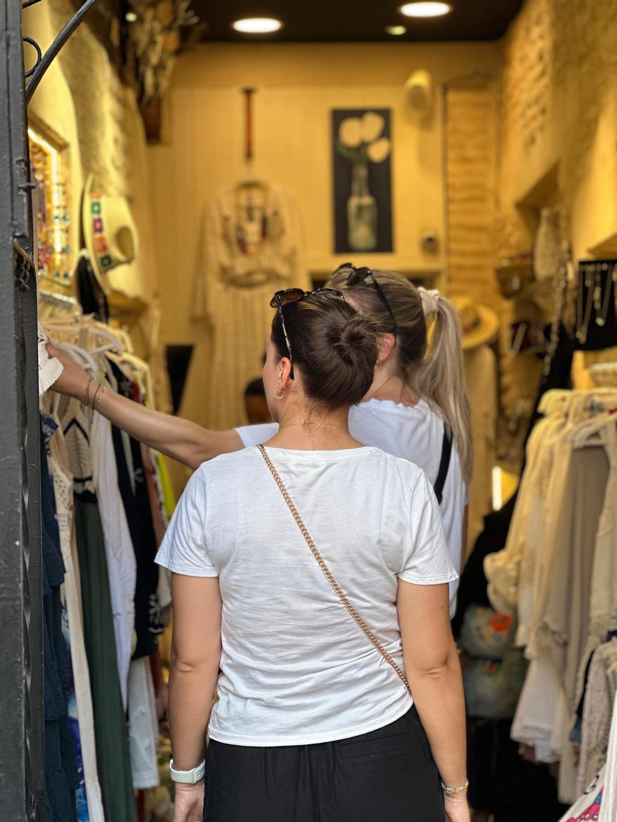 Dos turistas ojean ropa en una tienda del barrio de Santa Cruz.