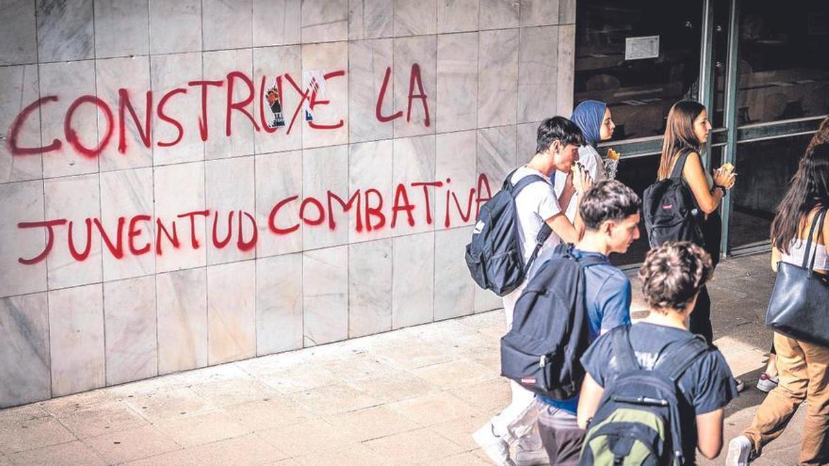 Un grupo de jóvenes delante de una pintada política en Barcelona.