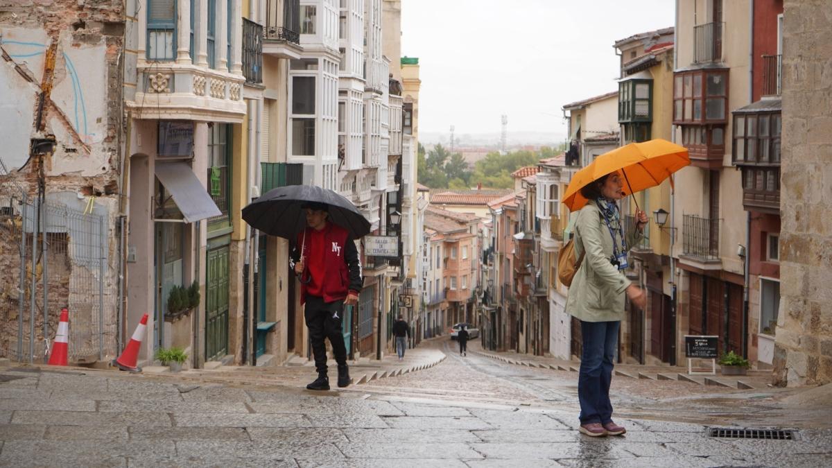 Dos personas se protegen de la lluvia en la calle Balborraz zamorana