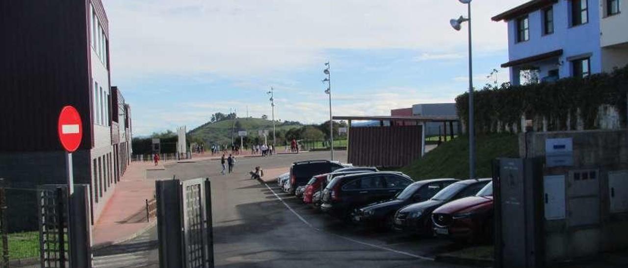 La verja de entrada al colegio de Colombres, abierta, con los niños en el recreo al fondo.