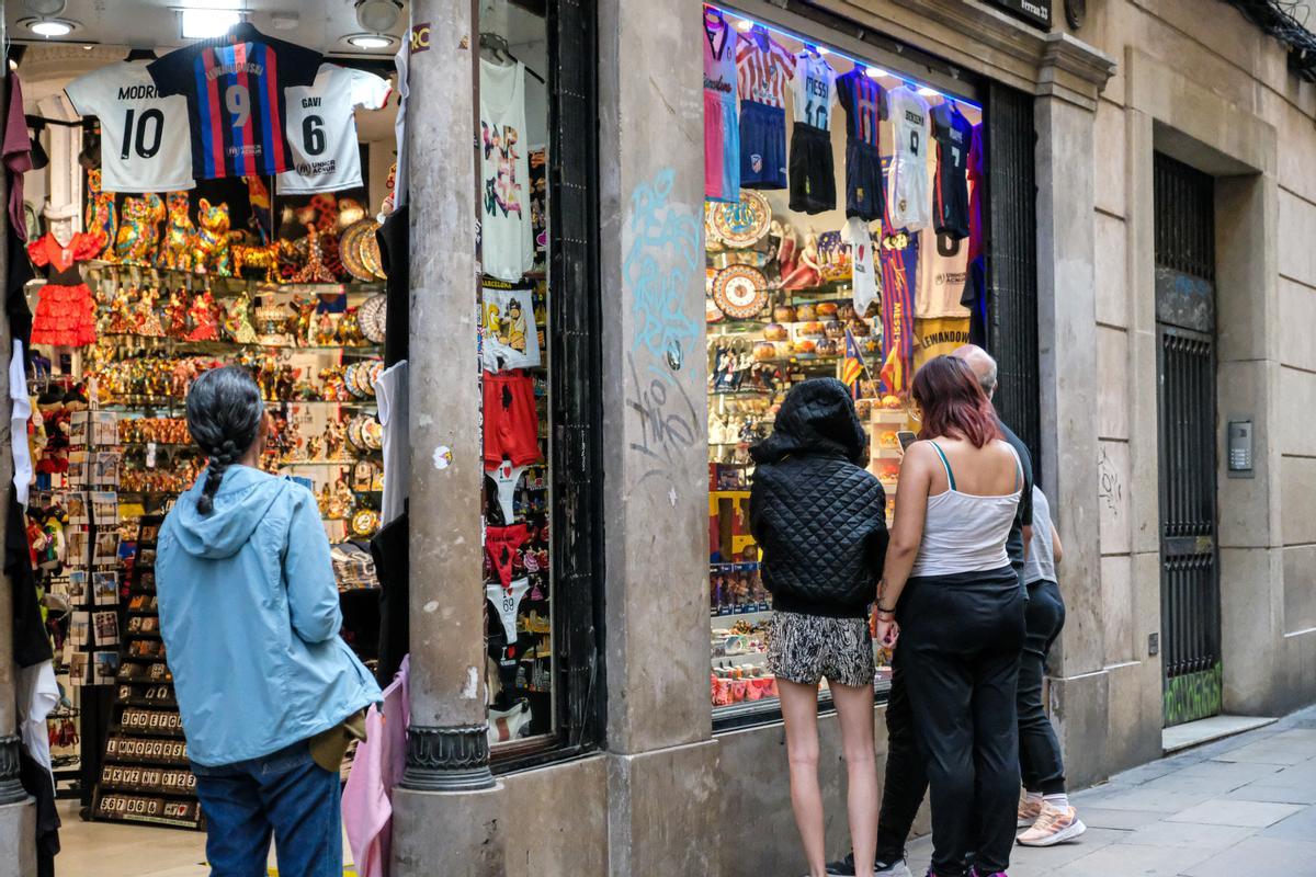 Unos turistas miran los artículos de una tienda de suvenires del Gòtic.