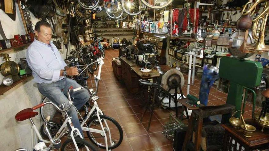 Amador, montado en su bicicleta estática favorita, entre los miles de objetos antiguos de todo tipo que guarda en su casa de Granja de Moreruela.
