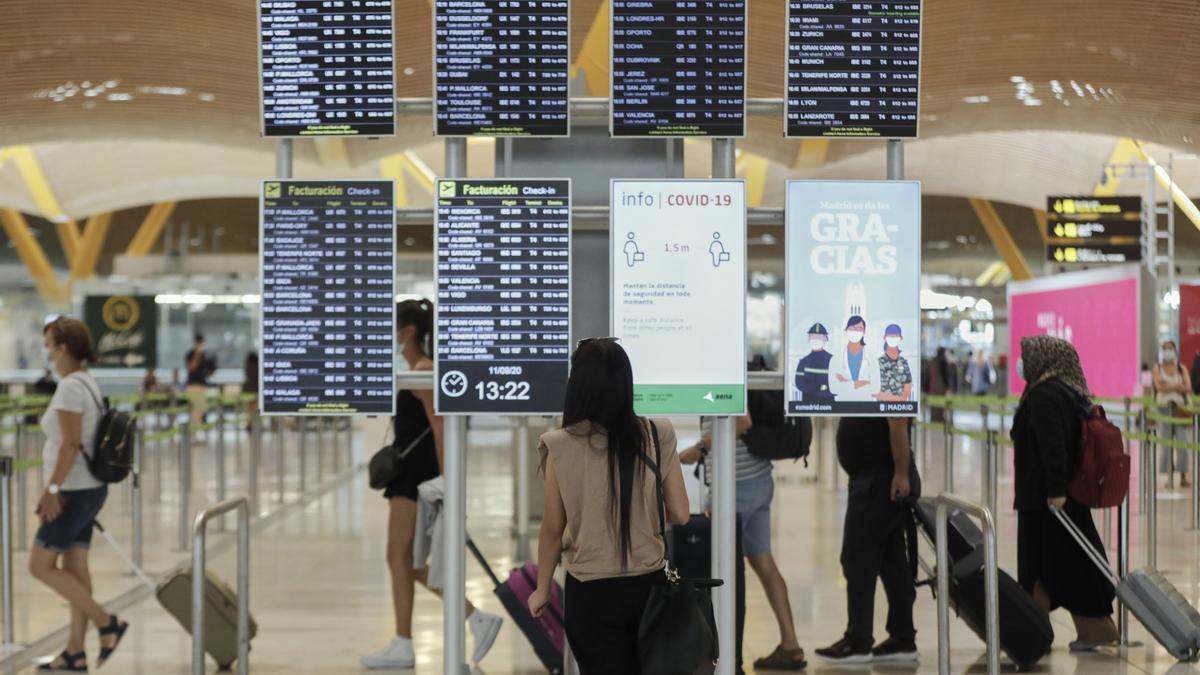 Archivo - Pasajeros cerca de páneles informativos en la terminal T4 del aeropuerto Adolfo Suárez Madrid-Barajas, en Madrid (España), a 11 de septiembre de 2020.