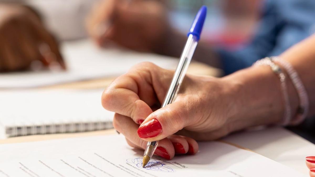 Una persona signa un document, en una imatge d'arxiu.
