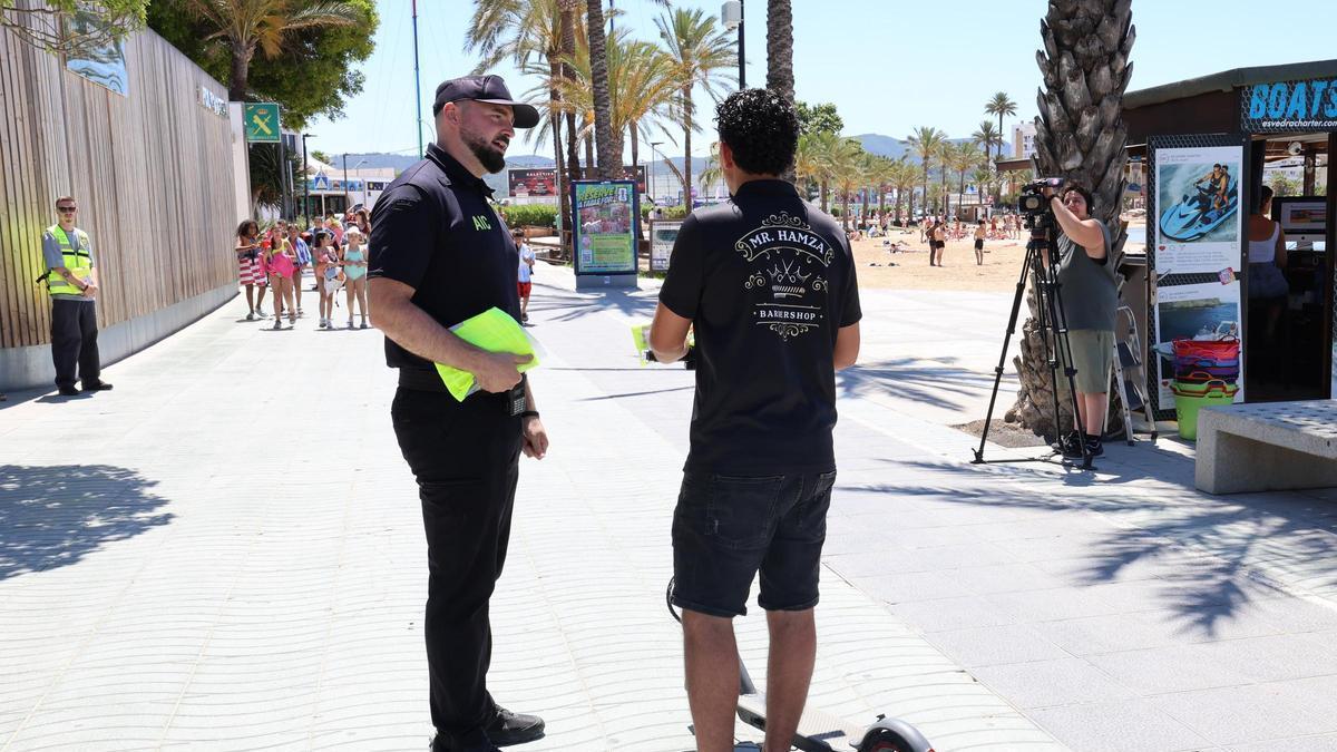 Un agente de policía da indicaciones a un usuario de patinete elétrico en el paseo de s'Arenal.
