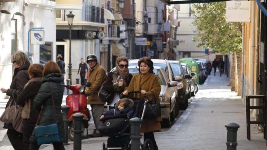 Dos mujeres de diferente edad portan un carrito de bebé por una de las calles de la ciudad.
