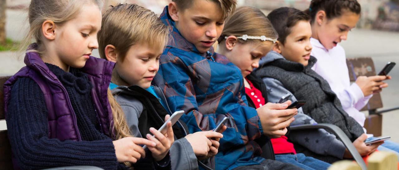 Varios niños consultan sus teléfonos móviles.