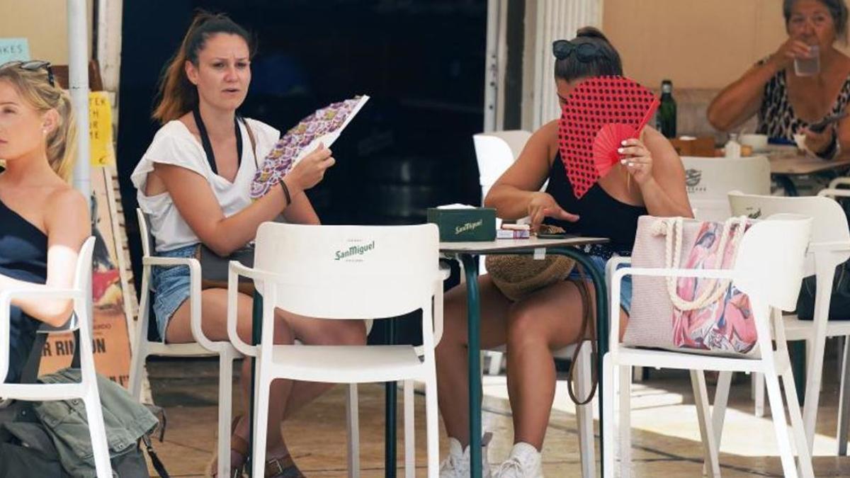 Dos mujeres combaten el calor en Málaga con abanicos.