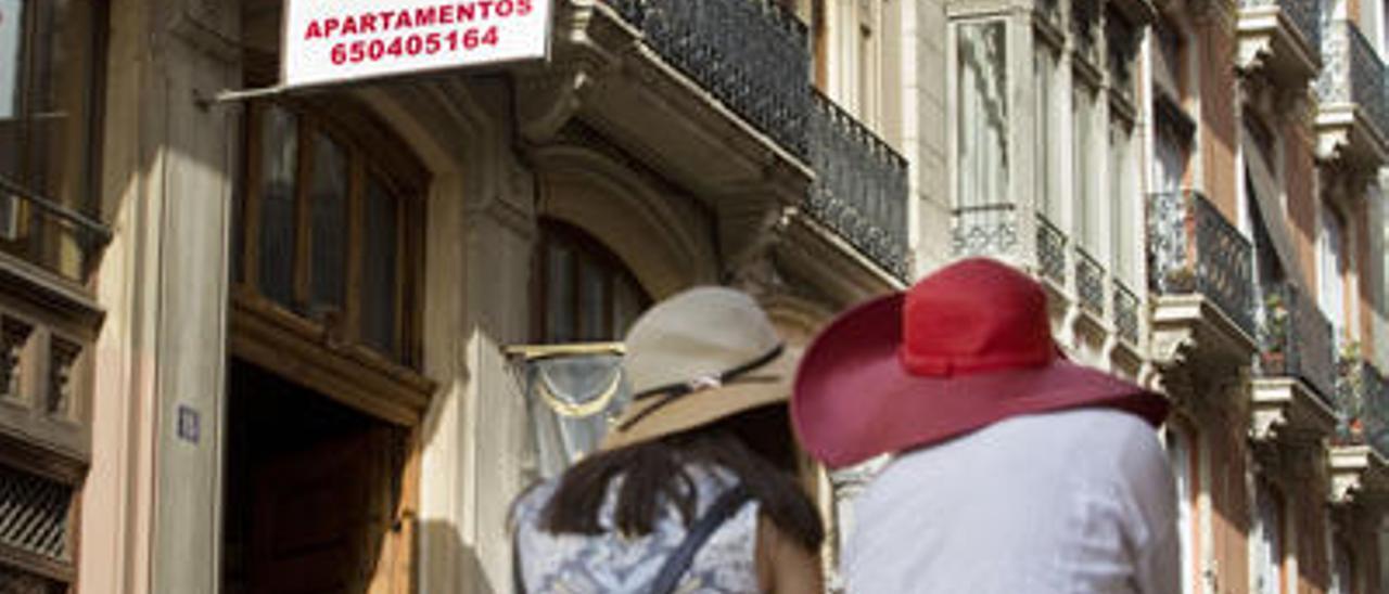 Dos turistas, ante un edificio que alquila apartamentos.