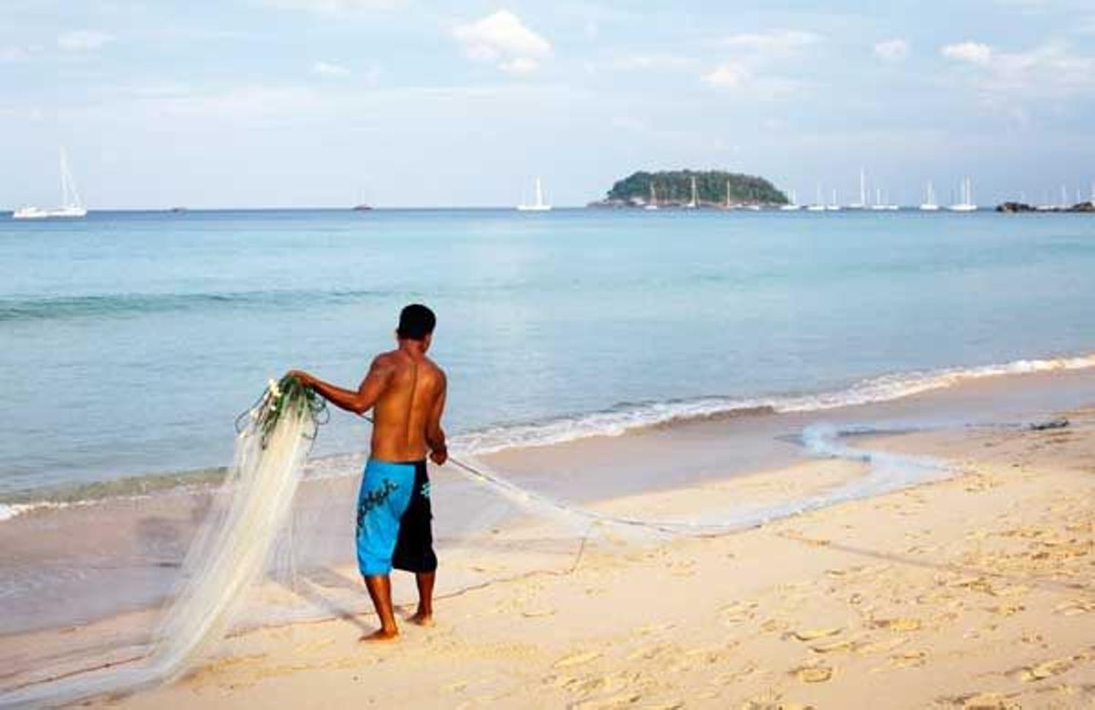 Hombre recogiendo las redes de pesca en la playa de Kata Noi, al sureste de Phuket.