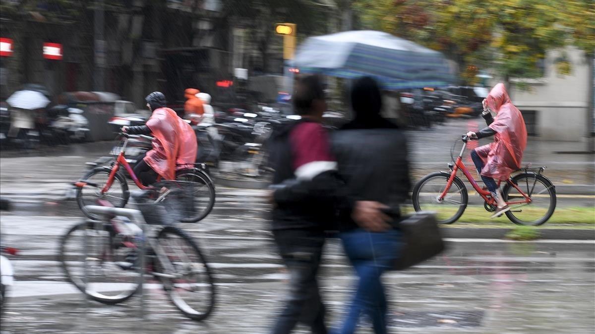 Los transeúntes se protegen de la lluvia en Barcelona.