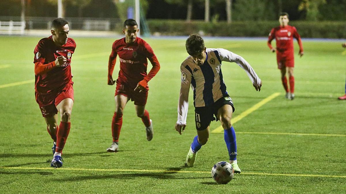 Abde avanza con el balón mientras Tendillo y Calvo intentan cruzarse para frenarle.