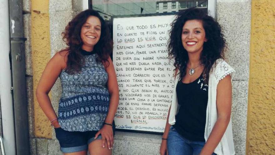 María e Inma, junto a la ventana en la que se ve la pizarra en la que escriben las diferentes frases. // D.P.