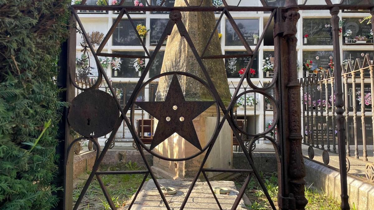 Detall de la porta de ferro amb simbologia maçònica que forma part de la tanca per tal de protegir el mausoleu del difunt Enrique Serra Cássa, al cementiri de Figueres.