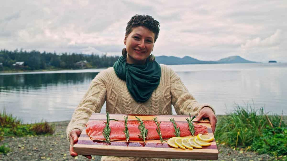 Una mujer sujeta un salmón rojo de Alaska listo para cocinar.