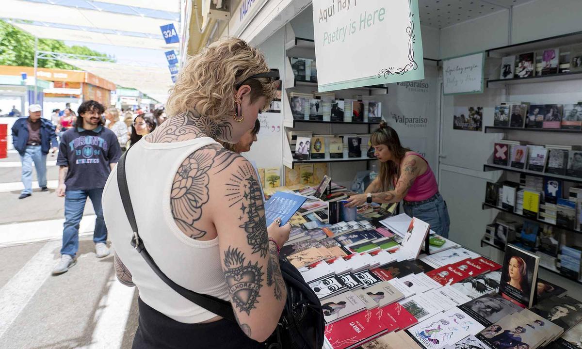 Una lectora hojea un poemario en un puesto de la Feria del Libro de Madrid.