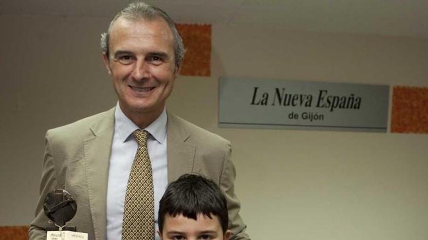 Óscar Luis Celada posa con la estela de Legazpi junto a su sobrino Roberto, que sujeta la caricatura del premiado.