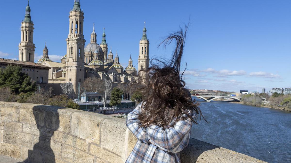 El viento mueve el cabello de una mujer en el puente de Piedra de Zaragoza