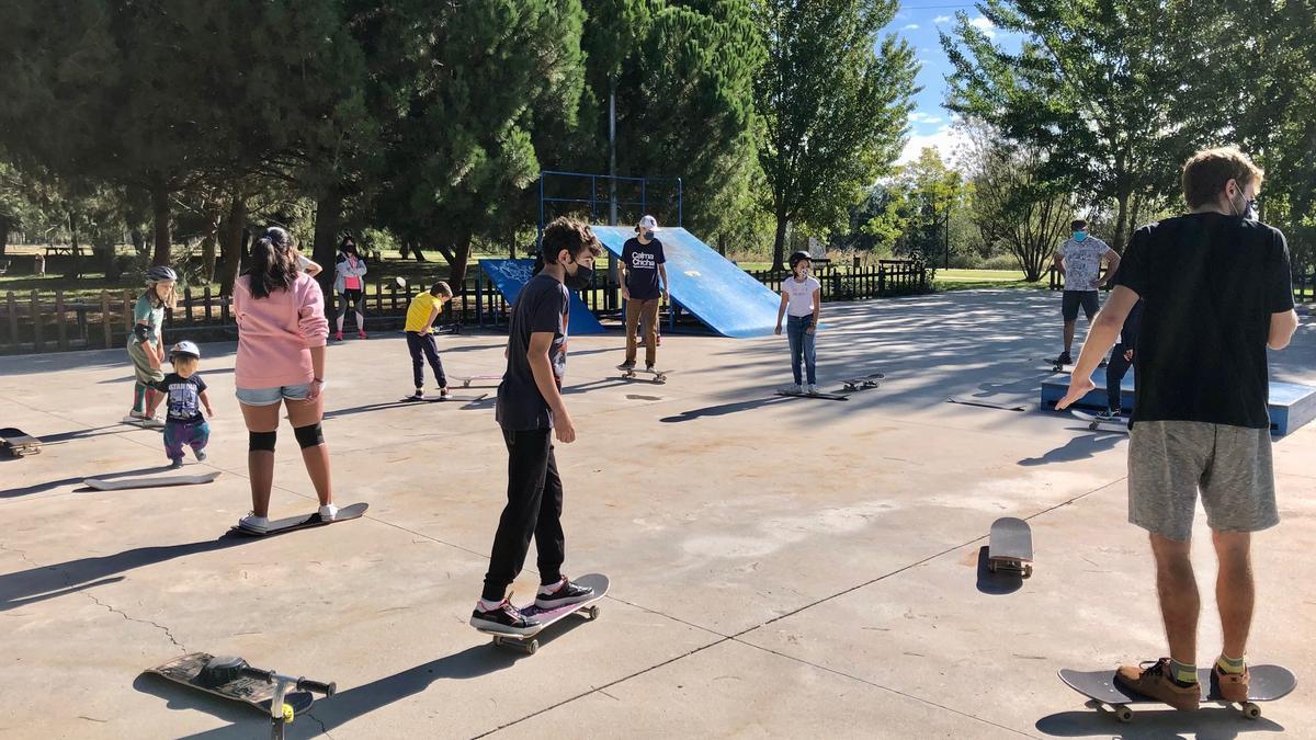 Varios niños de diferentes edades practican en una de las clases en la pista de skate.