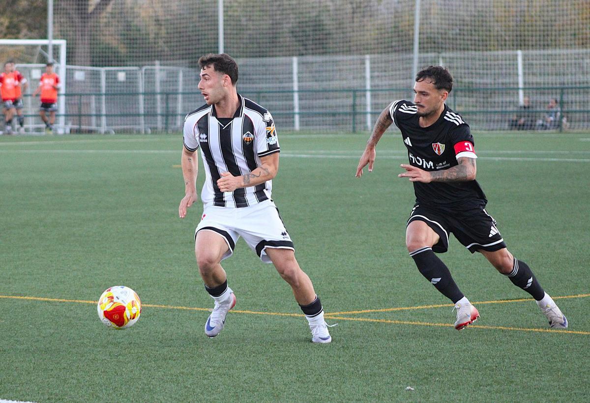 Nico Font conduce el balón ante la presencia de un futbolista del Barbastro.