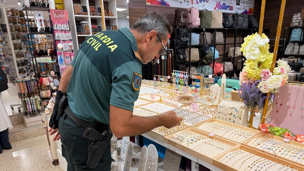 Un agente de la Guardia Civil examina las piezas de bisutería falsificadas.