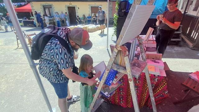 Un padre hojea con su hija un libro infantil en Cenera. | D. M.