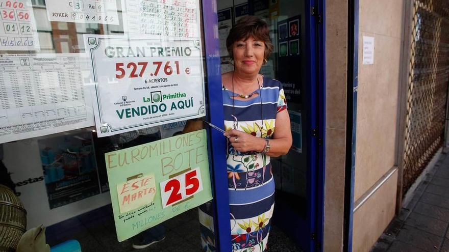 Amelia García Suárez muestra a la puerta de su administración un cartel con el premio de la primitiva que dio.