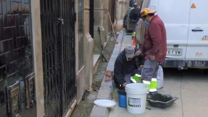 Els operaris realitzant les tasques d&#039;arrenjament de la vorera del carrer del Castell