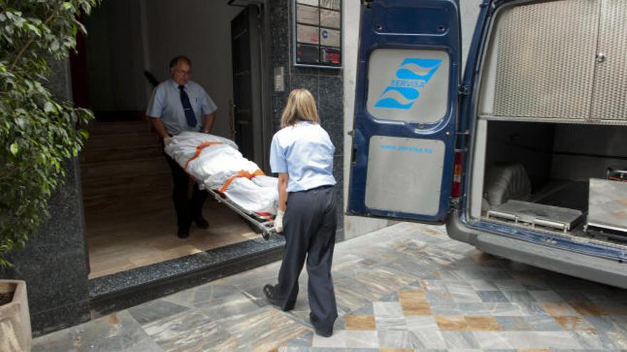 Empleados de los servicios funerarios trasladan el cadáver de R.M., el sacerdote jubilado que ha sido encontrado hoy muerto en su casa, ubicada en el centro de Cartagena, en la que, según han advertido los agentes de la Policía Nacional que han acudido al lugar, se había perpetrado un robo