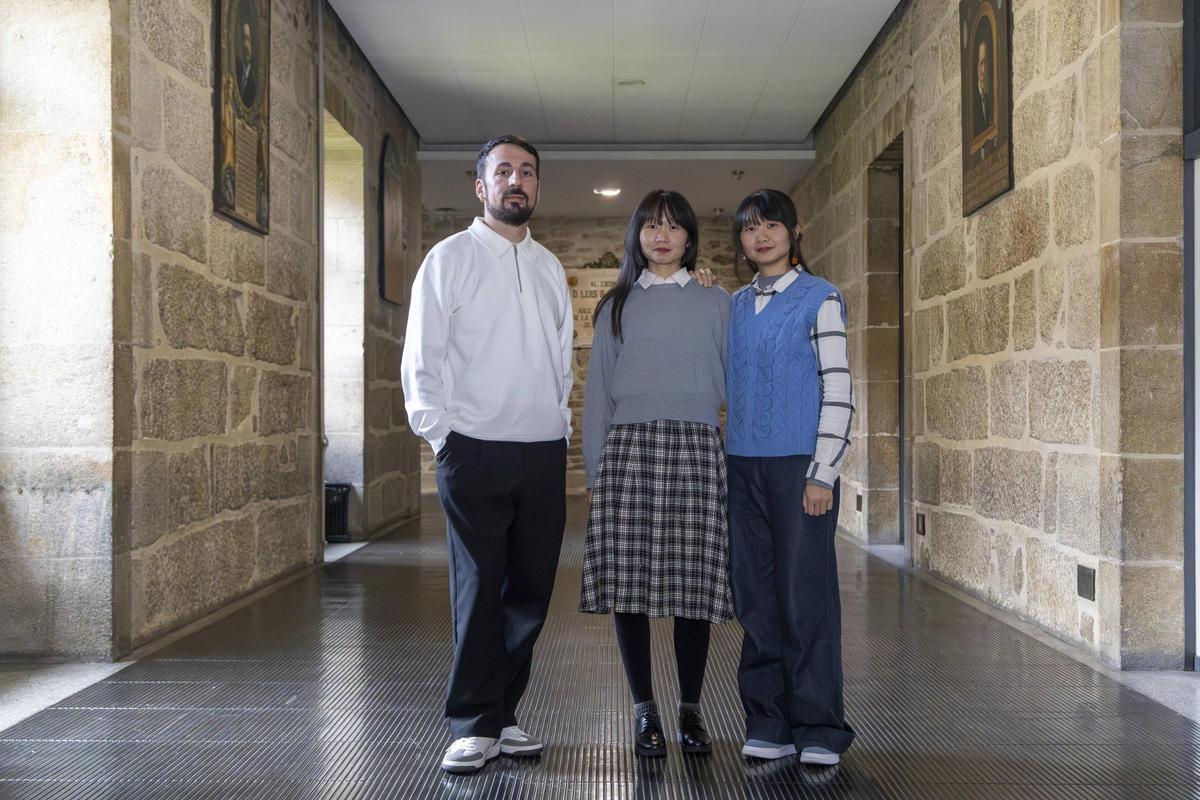 Eduardo Rial, Sixing Xu y Siyi Xu, exalumnos de la escuela Mestre Mateo, posan en los pasillos de la Facultade de Historia de la USC.