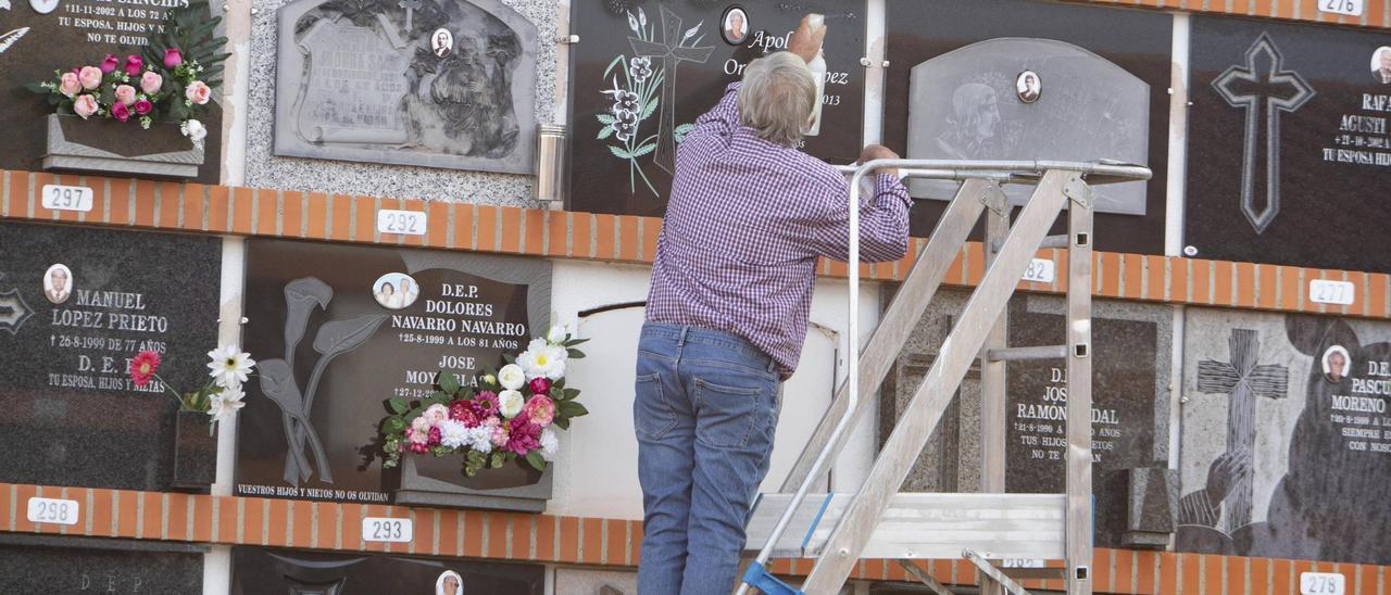 Un hombre limpia una lápida en el cementerio de Xàtiva.