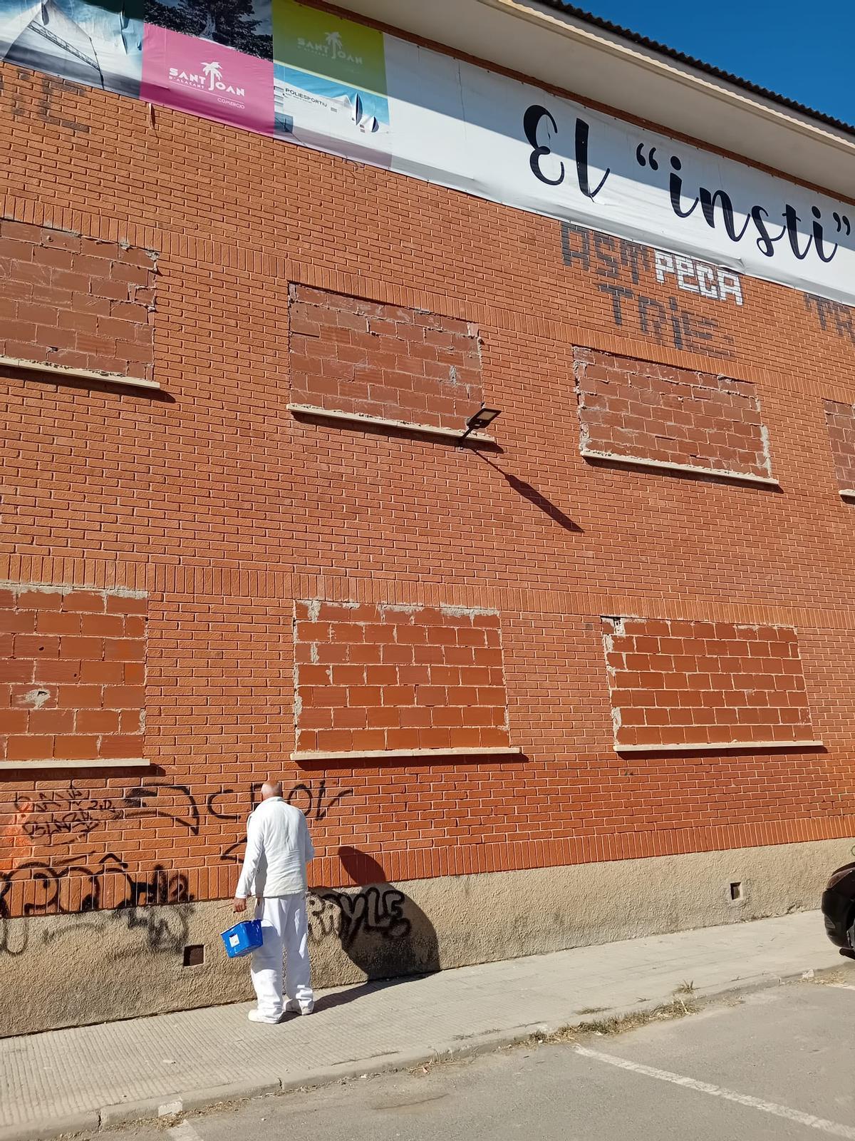 Un hombre quita los grafitis de la fachada