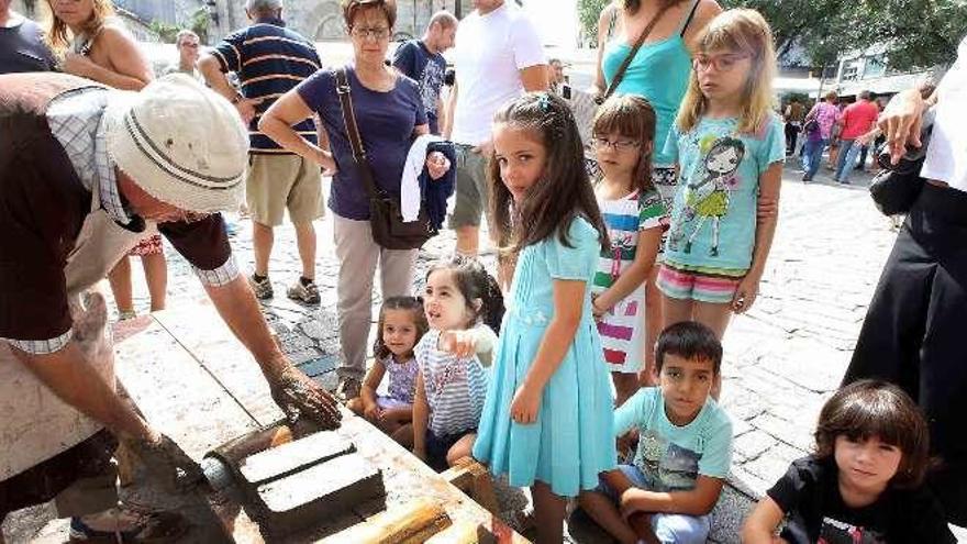 Unos niños contemplan como se fabrican tejas, en la feria. // A.H.