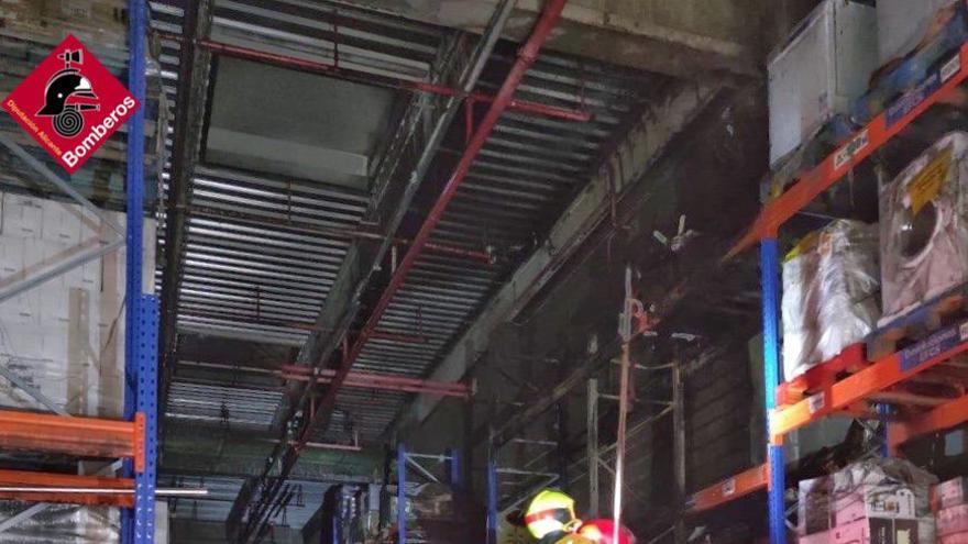 Los bomberos revisan los daños en el almacén.