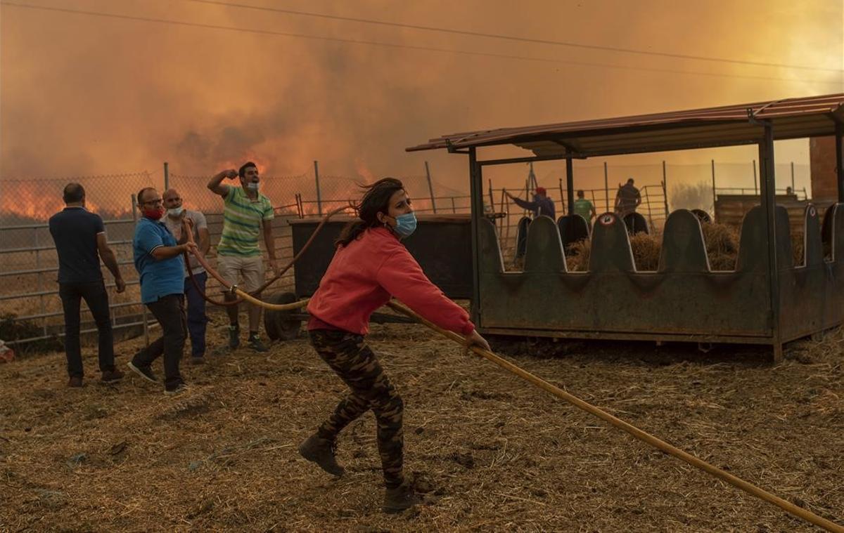 Una mujer ayuda en las tareas de extinción de un incendio cerca de una nave ganadera en Vegalatrave,  Zamora, el 15 de agosto del 2020.