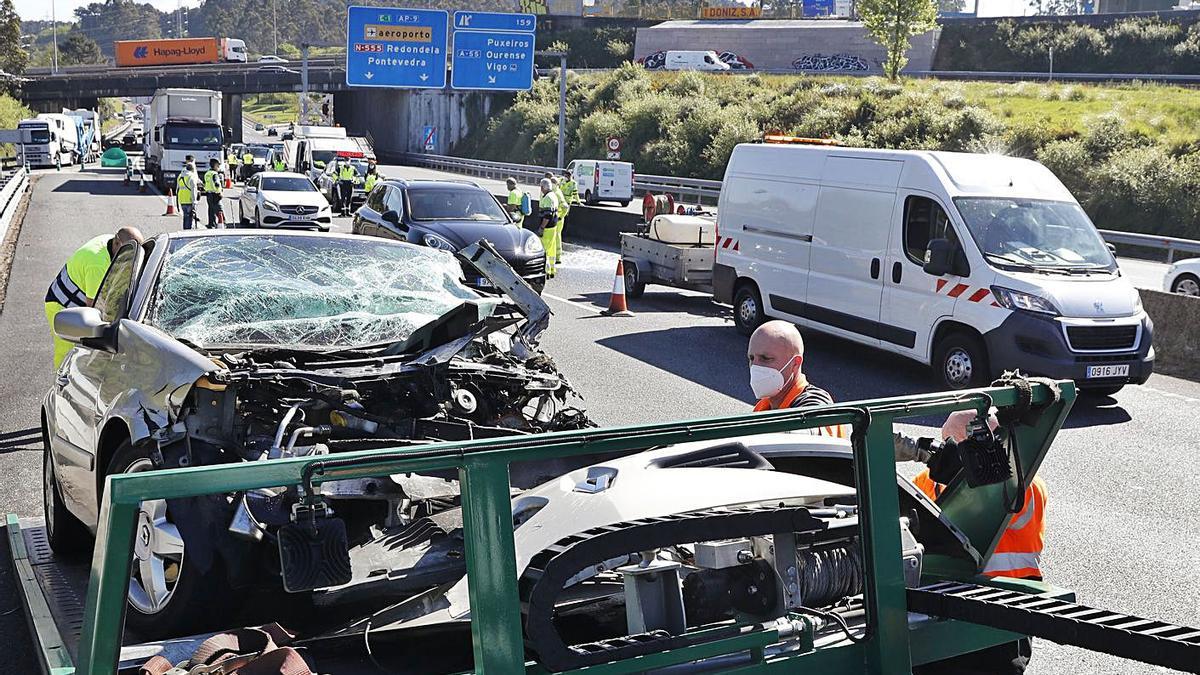 Operarios de la grúa retiran el coche siniestrado en la AP-9, a su paso por Puxeiros. |   // RICARDO GROBAS